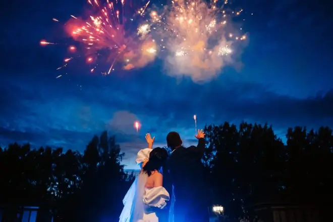 Wedding guests laughing and enjoying interactive entertainment at an outdoor evening reception