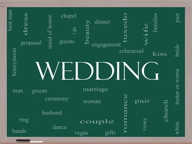 Couple reviewing wedding planning documents together at a table with floral arrangements