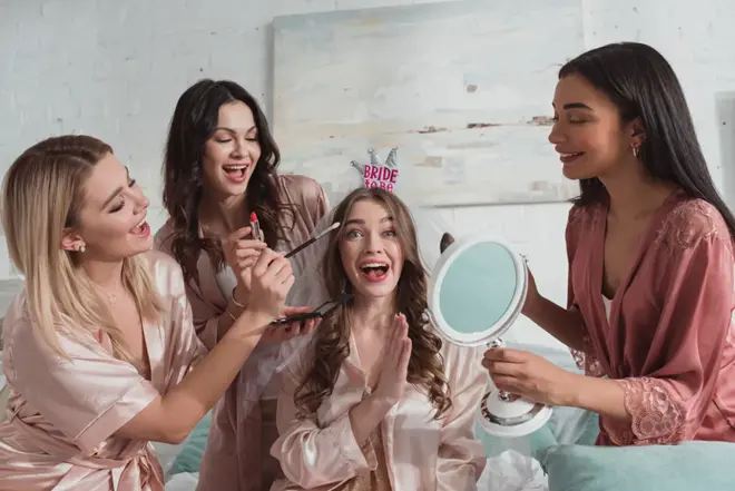 Group of women laughing together at a decorated bridal celebration with gifts and champagne
