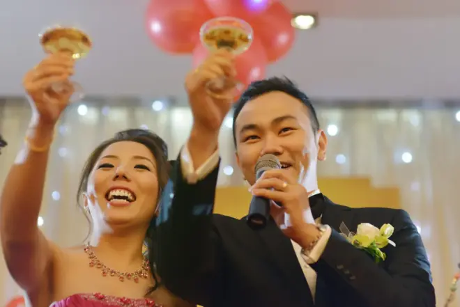 Wedding guest standing and raising a champagne glass to toast the newlywed couple at a reception dinner