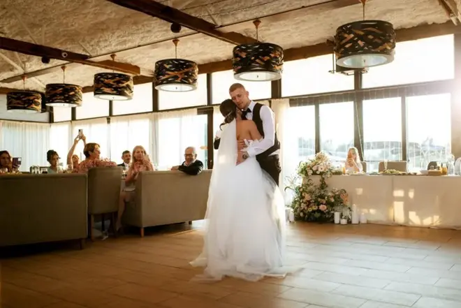 Newlywed couple sharing their first dance on a softly lit dance floor at their wedding reception