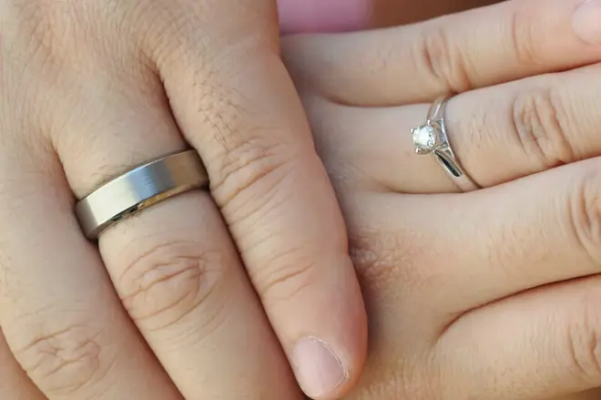 Close-up of a wedding ring resting on a velvet surface beside insurance documents