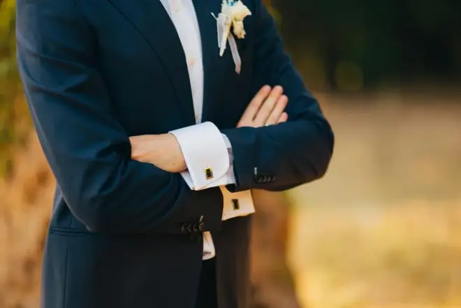 Groom wearing a colorful suit with a boutonniere outside a city hall building