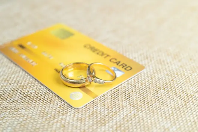 Couple reviewing wedding budget together with rings and planning materials on the table