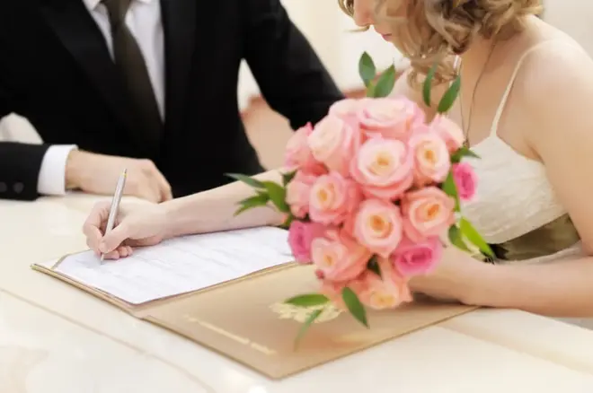 Couple reviewing a wedding vendor contract together at a table with planning documents