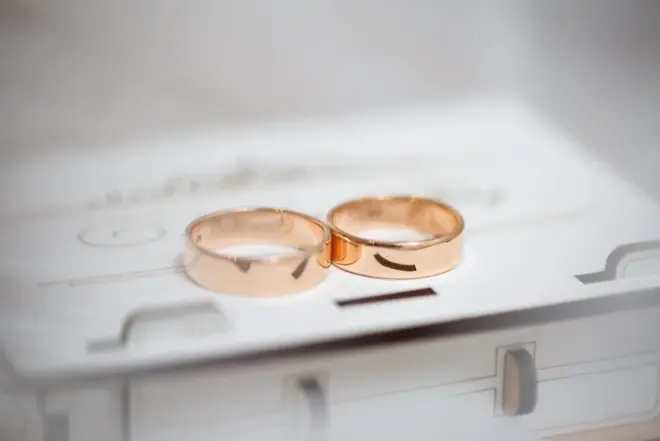 Two gold wedding bands resting side by side on a soft white surface