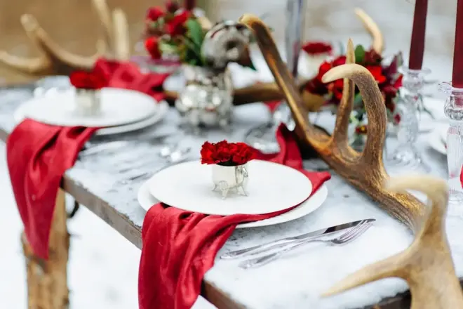 Winter wedding table setting with candles, evergreen branches, and seasonal flowers in a warmly lit venue